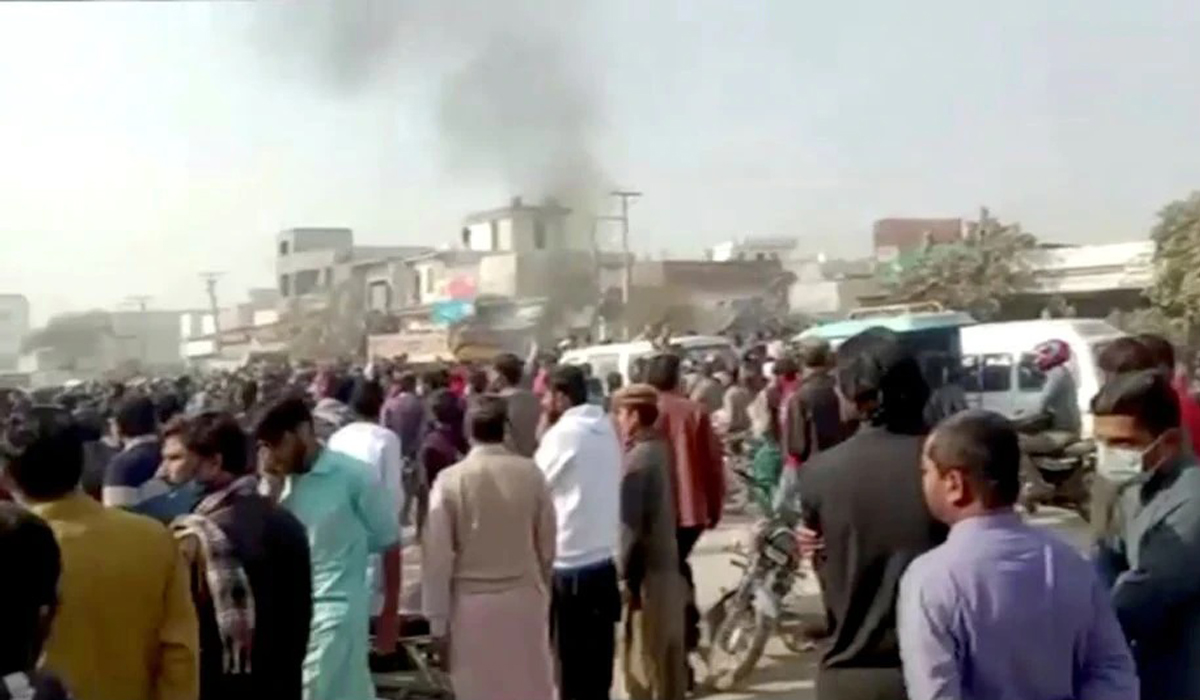 People gather after an attack on a factory in Sialkot
